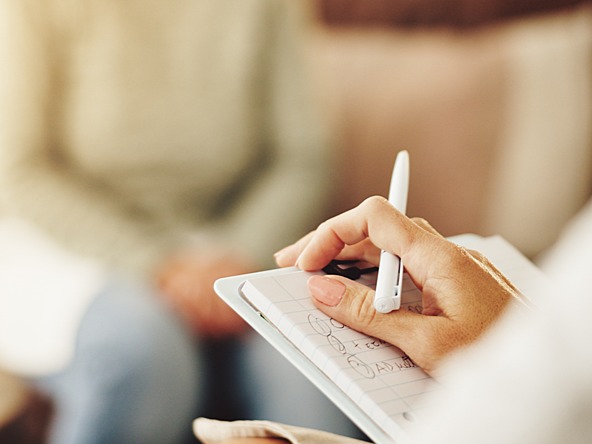 person taking notes in therapy counselling session 